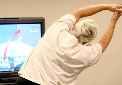 A senior stretches along to a video fitness class