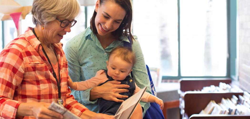 Mom and baby getting recommendation on book from a librarian