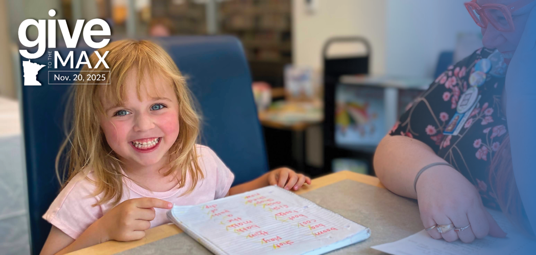 Smiling girl reading with a librarian at Hennepin County Library