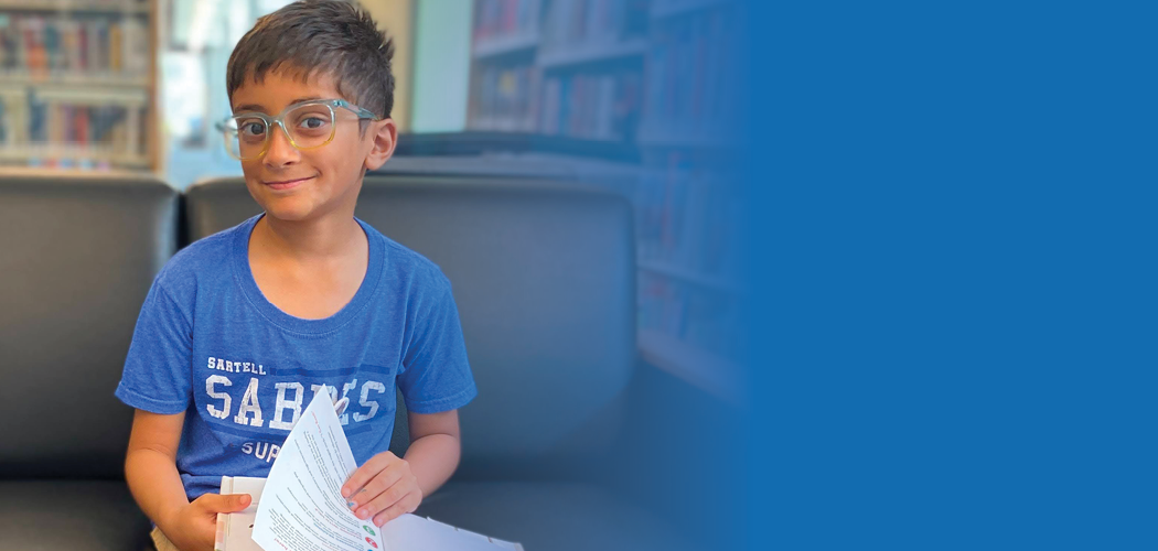Child reading a book on a sofa.