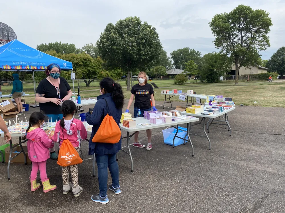 Librarians gives children books in the park