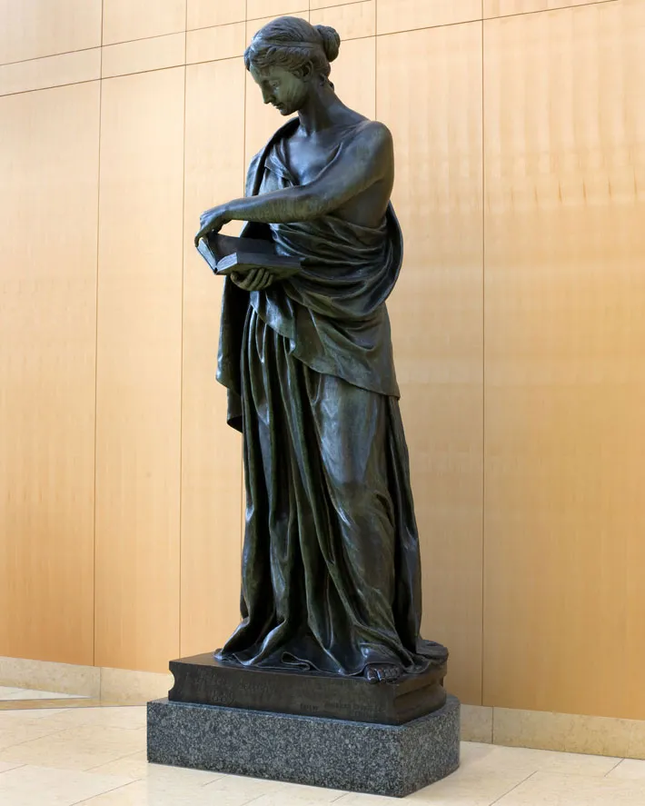 A large statue of a woman reading a book at the entrance of Minneapolis Central Library