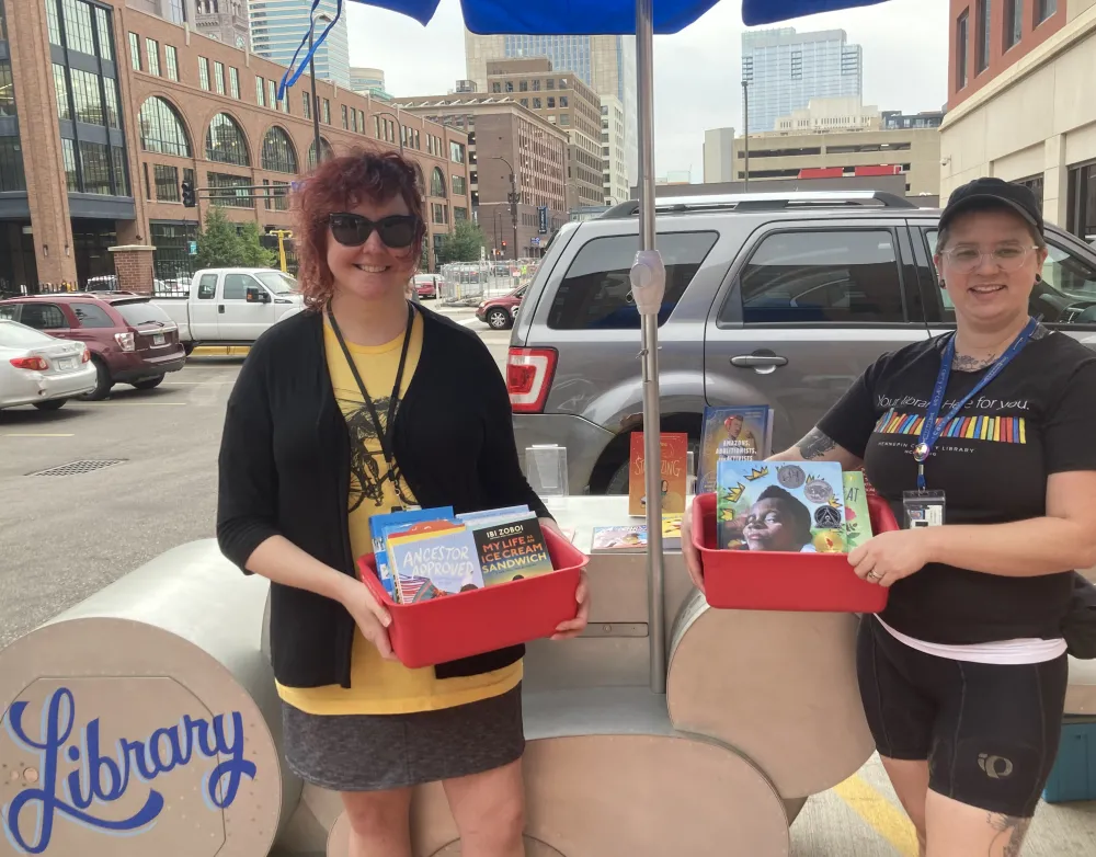 Librarians Kelly and Zee pose with the library bike .