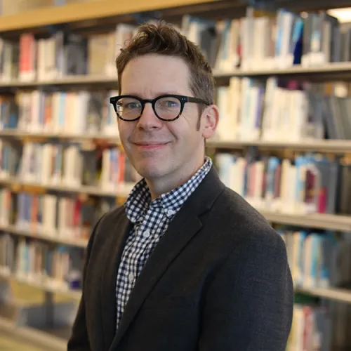 Portrait of Adam Breininger in front of the stacks at Minneapolis Central Library