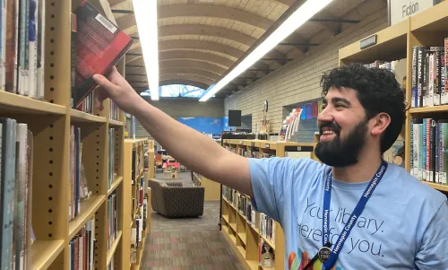 Rafael smiles as he returns a book to the stacks at Augsburg Park Library.