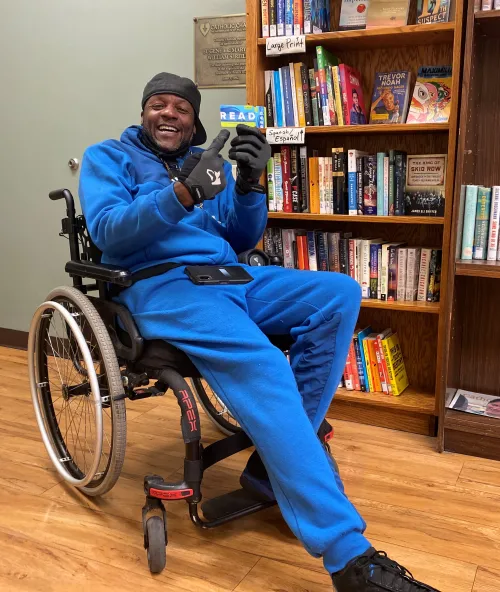 An eager patron poses with his new library card at the Opportunity Center shelter. 