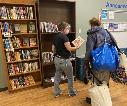 Zee Recommends a Book to a patron at a homeless shelter. 