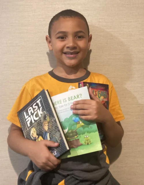 At a local homeless shelter, a young boy poses with his new books. 