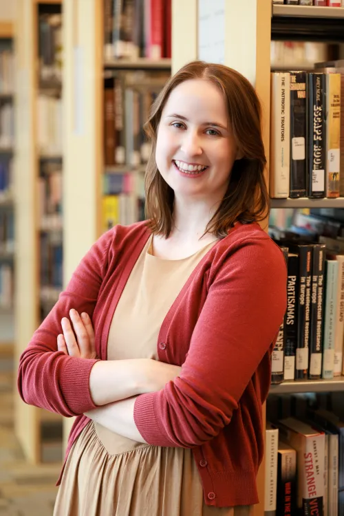 Laura Graveline smiling in front of the stacks at Minneapolis Central Library