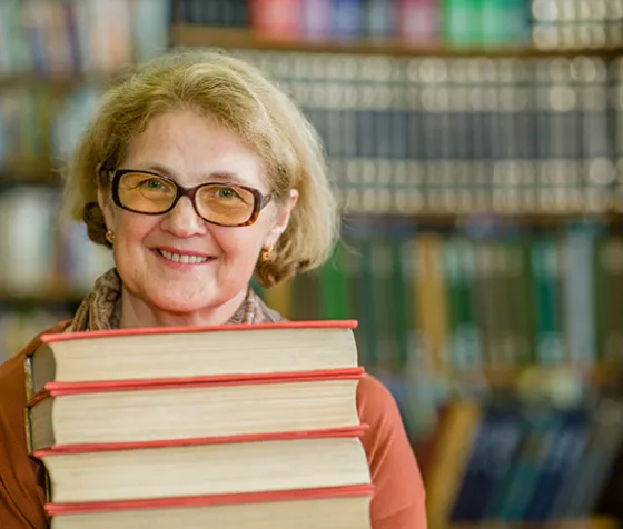 Smiling woman with books in library space