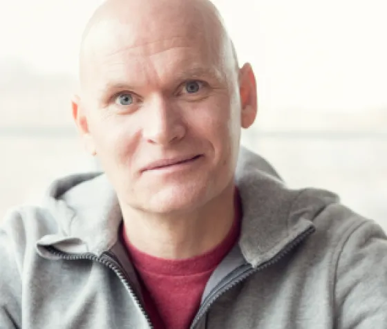 Headshot of author Anthony Doerr in a red shirt and gray sweatshirt
