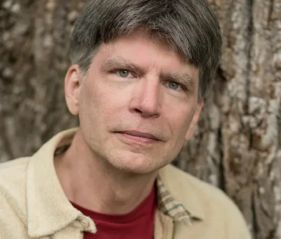 Headshot of author Richard Powers against a tree