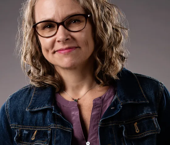 Headshot of author Kim Heikkila in a blue coat in front of a gray background