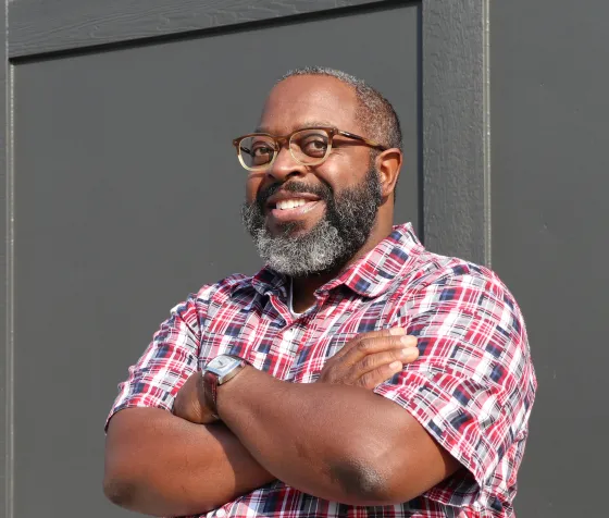 Picture of author Michael Kleber-Diggs smiling and standing against a wall