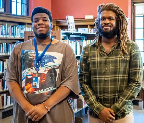 Johnny and Thomas standing among stacks at Sumner Library