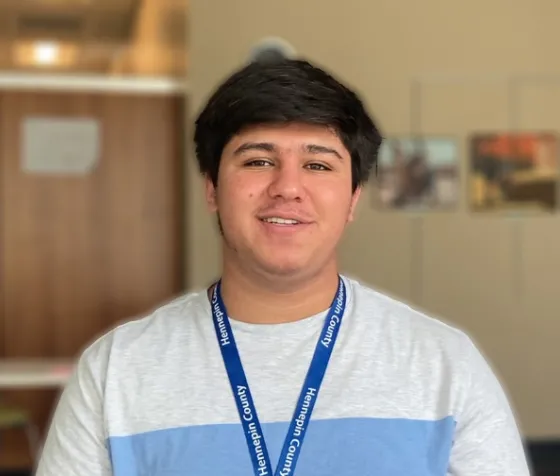 Irfan wearing Hennepin County Library batch and smiling
