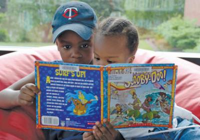 Two kids reading a book in a beanbag chair