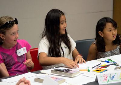 Three children seated a table with art supplies