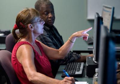 Two adults use a computer at job resource workshop