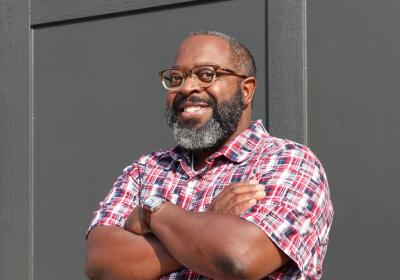 Picture of author Michael Kleber-Diggs smiling and standing against a wall