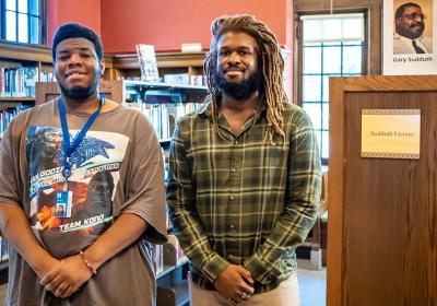 Johnny and Thomas standing among stacks at Sumner Library