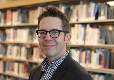 Portrait of Adam Breininger in front of the stacks at Minneapolis Central Library