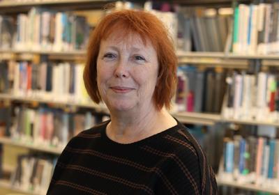 Portrait of Linda Merritt in front of the stacks at Minneapolis Central Library