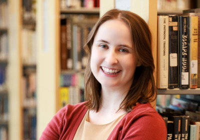 Laura Graveline smiling in front of the stacks at Minneapolis Central Library