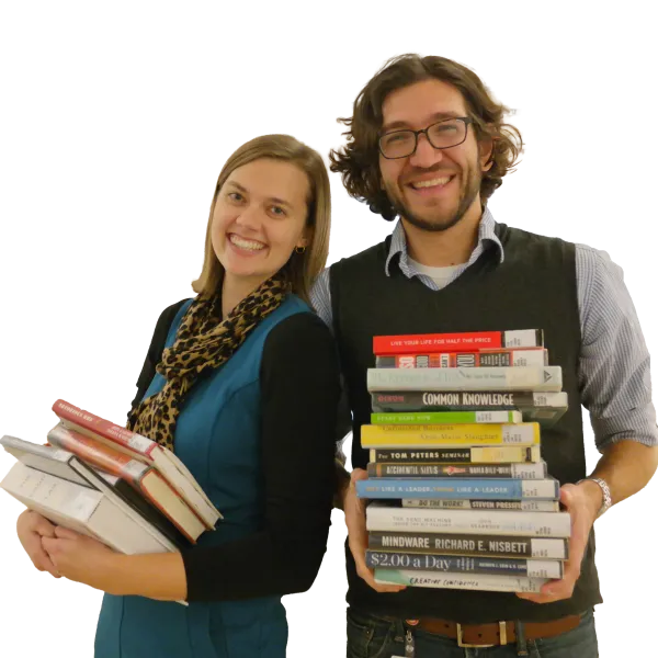 Two adults holding stacks of books