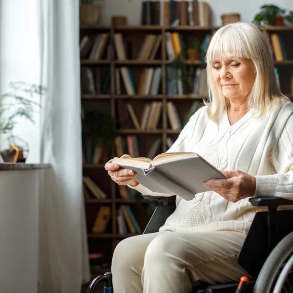 A woman in a wheelchair reading by the window