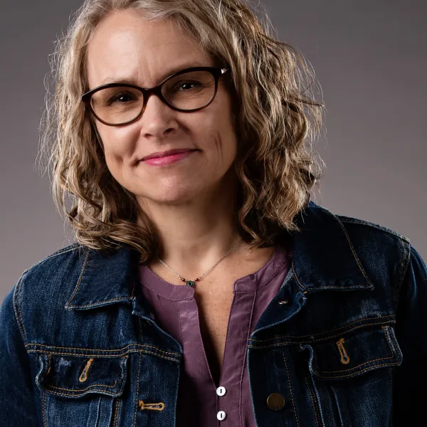 Headshot of author Kim Heikkila wearing a blue jacket in front of a gray background