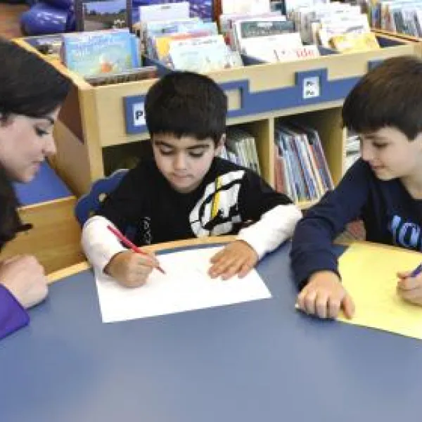 two kids and adult doing homework at the table