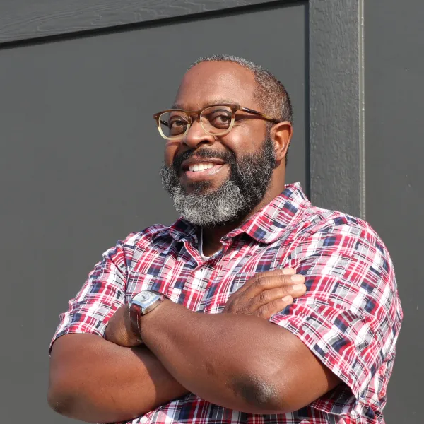 Headshot of author Michael Kleber-Diggs smiling and standing against a wall