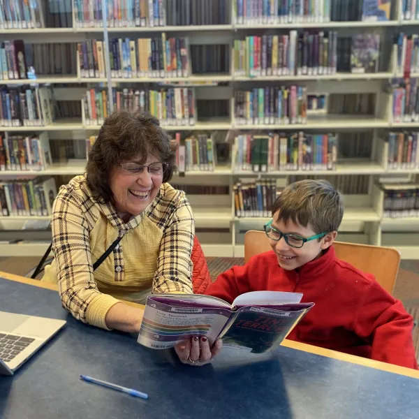 Brody and his tutor, Sue, read together at Brookdale Library and laugh. 